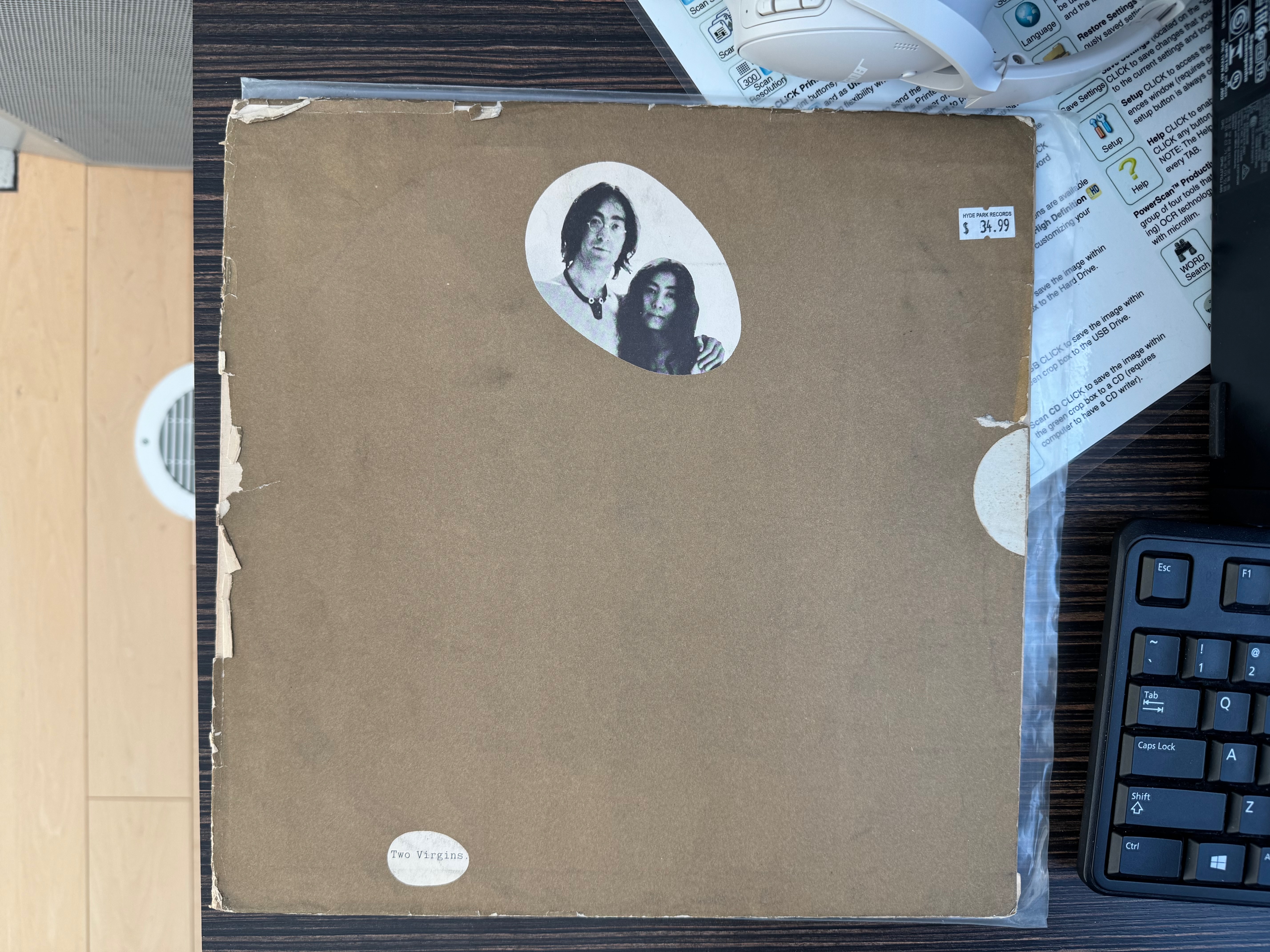 a copy of John Lennon and Yoko Ono's Two Virgins album sitting on a desk, with a $34.99 price tag affixed, next to a keyboard and pair of headphones